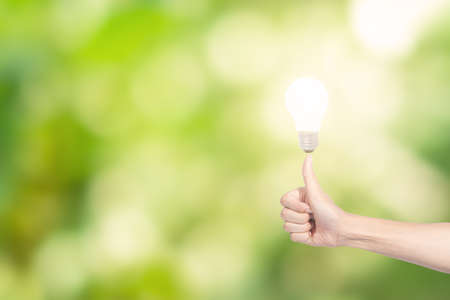 Human hand concept, saving energy from light bulbs, natural bokeh backgroundの写真素材