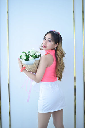 Portrait of a beautiful woman in a pink dress, white skirt holding a bouquet of flowers on Valentine's Dayの写真素材