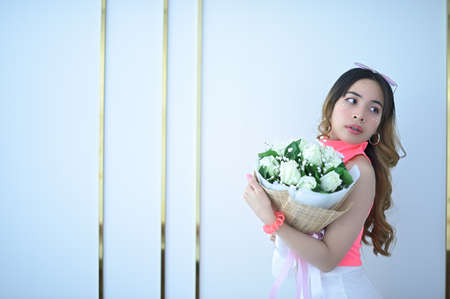 Portrait of a beautiful woman in a pink dress, white skirt holding a bouquet of flowers on Valentine's Dayの写真素材