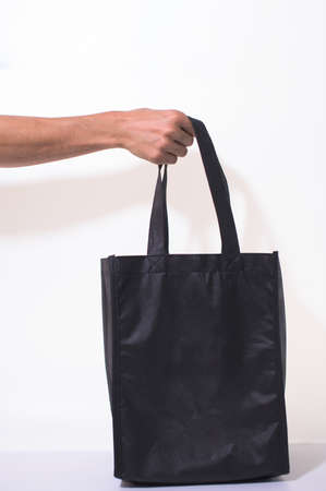 Holding a black cloth bag on a white backgroundの写真素材