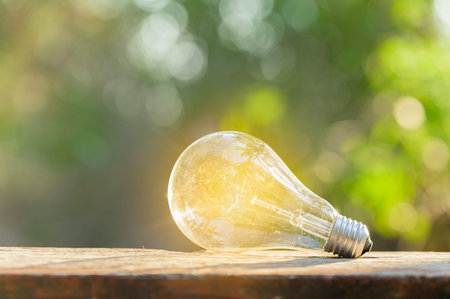 A light bulb shining brightly placed on a wooden floor Bokeh background scene Natural green