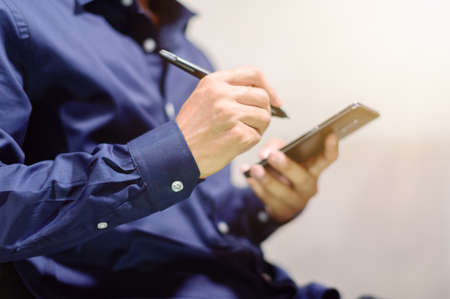 Business people use a smartphone with a pen to take notesの写真素材
