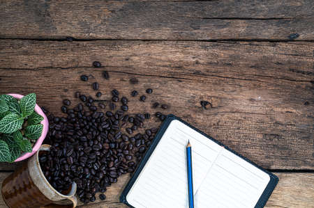 Notepad pencil and coffee beans are on the desk top viewの写真素材