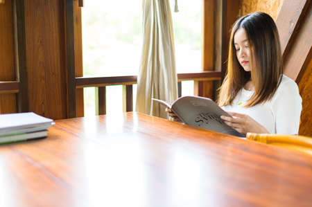 beautiful woman sitting in a cafe reading a bookの写真素材