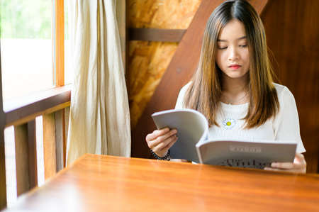beautiful woman sitting in a cafe reading a bookの写真素材