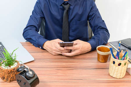 Businessmen use smartphones at their desks in the room.の写真素材