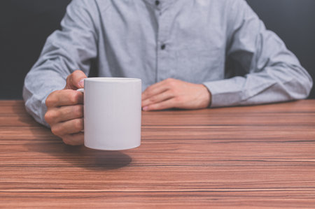 man holding a coffee cup at his deskの写真素材