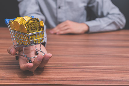Hand holding a shopping cart to put money business ideas earn moneyの写真素材
