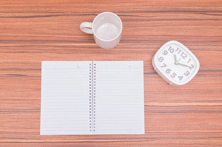 The notebook and the clock are on the table.