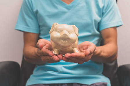 Hand holding a piggy bank, money saving conceptの写真素材