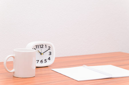 The notebook and the clock are on the table.