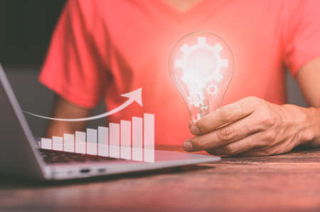 hand of a man with a light bulb And there is a gear icon planning and strategy, Stock market, Business growth, progress or success concept.の写真素材