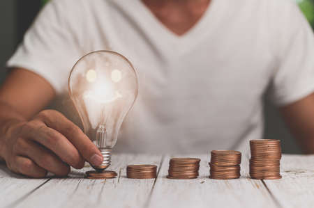 businessman holding lightbulb money stack idea saving energy and accounting financeの写真素材