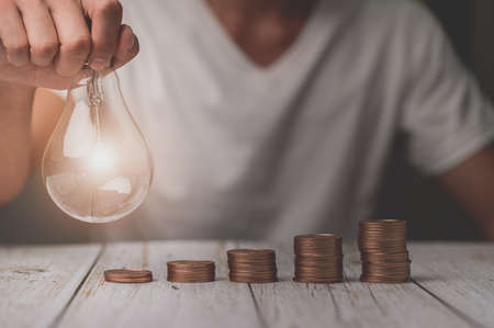 businessman holding lightbulb money stack idea saving energy and accounting financeの写真素材