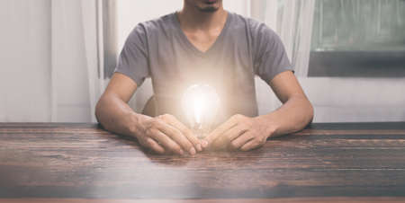 Man holding a light bulb, searching for ideas, new ideas, illustrationsの写真素材