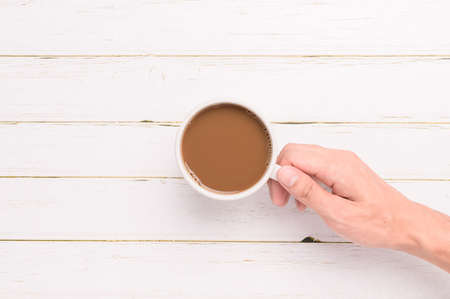 Hand holding a coffee mug on a wood backgroundの写真素材
