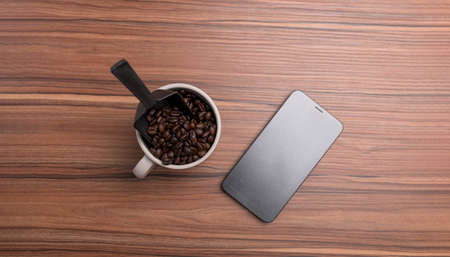 cup of coffee beans and a phone are on the desk.の写真素材