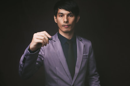 Businessman holding a pen, black backgroundの写真素材