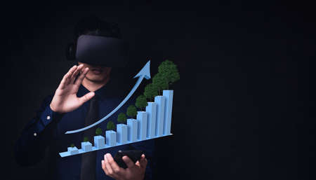 Businessman using Virtual Reality Metaverse glasses to virtual world showing bar graph business growthの写真素材