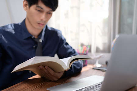 business man reading a book at his deskの写真素材