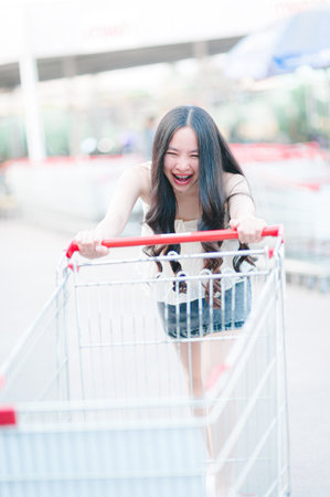 Asian woman pushing shopping cart in shopping mallの写真素材