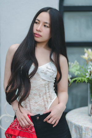 A striking portrait of a young woman showcasing her elegance in a stylish lingerie outfit. With long dark hair and a natural expression, she exudes confidence in a softly lit indoor setting.の写真素材