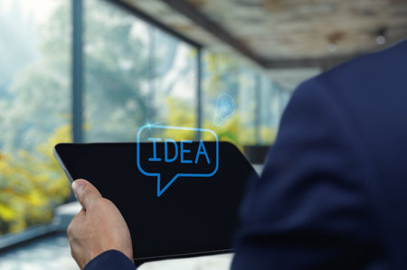 A business professional holding a tablet displaying the word "IDEA" in a modern office. This image captures the essence of creativity and innovation in the workspace.の写真素材