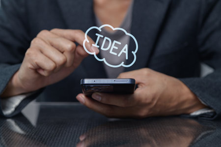 A person engages in creative thinking while using a smartphone, generating innovative ideas. The image captures the essence of brainstorming and inspiration in a modern, professional setting.の写真素材