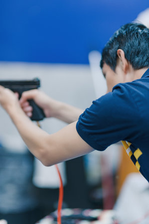 A person aims a firearm in an indoor shooting range, showcasing focus and concentration. The image captures the intense moment of practice, emphasizing safety and skill.の写真素材