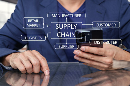 A businessman engaged in supply chain management, using a smartphone to analyze connections between customers, manufacturers, and distributors effectively.の写真素材