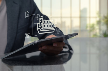A professional person examines a tablet displaying a supply chain management icon, symbolizing technology in logistics and modern business practices.の写真素材