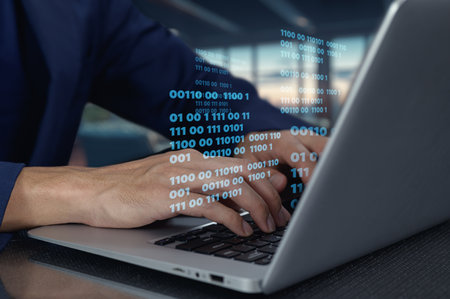 A close-up view of hands typing code on a laptop while binary data streams above. The image captures the essence of modern coding practices in a sleek workspace.の写真素材
