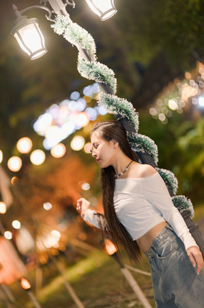 A joyful woman dances gracefully under glowing lanterns, surrounded by festive decorations. The enchanting evening atmosphere evokes feelings of celebration and happiness.の写真素材