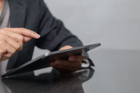 A person interacts with a tablet, showcasing a focused gesture. This close-up scene emphasizes...