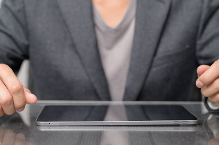 A close-up of a business person's hands resting on a sleek tablet device, showcasing a modern workspace setting that emphasizes professionalism and technology.の写真素材