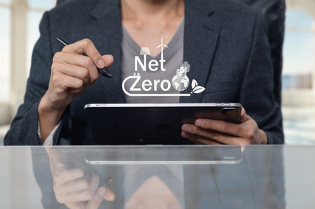 A business professional using a tablet to strategize for a sustainable Net Zero initiative. The image captures the essence of eco-friendly planning and corporate responsibility.の写真素材