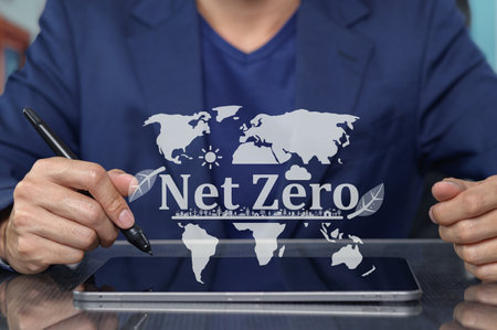 A businessman presents the Net Zero concept, emphasizing sustainability and ecological responsibility, with global maps and nature elements in a modern office setting.の写真素材