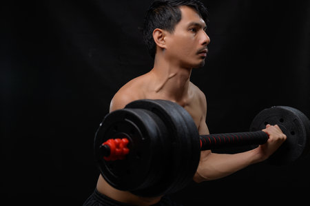 A focused athlete engages in strength training with a barbell, showcasing dedication to health and fitness. The dark background adds intensity to the workout scene.の写真素材