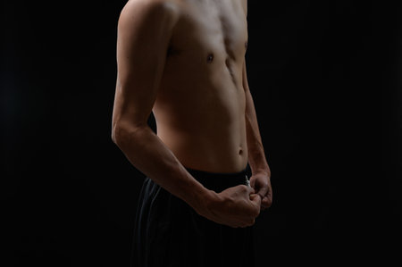 This striking image captures a muscular male torso flexing against a dark background, showcasing the dedication to fitness, strength, and overall health.の写真素材