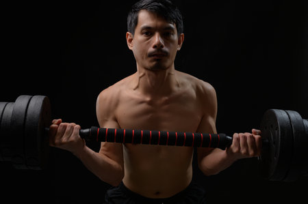 A focused man engages in strength training, lifting a dumbbell. This image captures the essence of fitness, health, and dedication to muscle development. Perfect for health and wellness themes.の写真素材