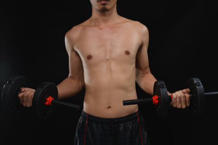 A dedicated individual lifts weights in a dark environment, emphasizing commitment to health and strength. This image captures the essence of fitness and motivation.の写真素材