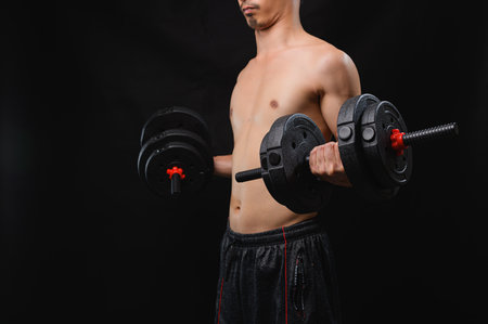 A young man engages in weightlifting with dumbbells, showcasing his dedication to fitness and health. The image represents strength training and physical wellness.の写真素材