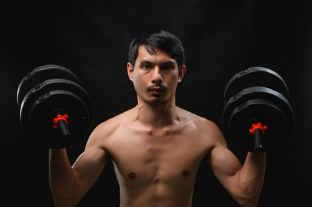 A strong man proudly lifts dumbbells, showcasing his dedication to fitness, strength, and health. This image captures the essence of intense training and motivation.の写真素材