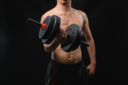 A muscular individual holds a dumbbell in a focused pose, symbolizing strength and commitment to fitness and health. Perfect for wellness and workout themes.の写真素材
