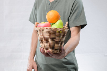 A vibrant assortment of fresh fruits including oranges, apples, and pears is presented in a wicker basket, symbolizing health and wellness.の写真素材