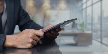 A person uses a tablet in a bright, modern office space, showcasing a blend of technology and professional lifestyle. The setting features natural light and contemporary design.の写真素材
