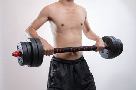 A strong male athlete demonstrates his power while lifting a barbell in a gym. The image captures the essence of fitness training, motivation, and strength.の写真素材