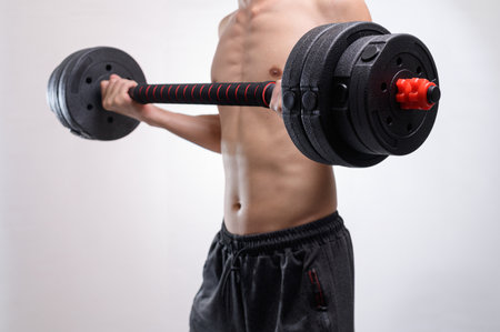 A fit individual demonstrates strength training by lifting a dumbbell. This image captures dedication to fitness and the pursuit of a healthy lifestyle.の写真素材