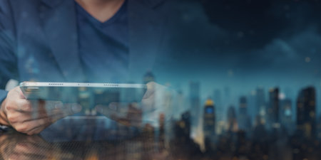 A person engages with a tablet device, surrounded by a night cityscape. The scene captures the blend of technology and urban life, showcasing modern connectivity.の写真素材