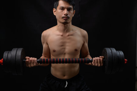 A focused male athlete lifting heavy dumbbells showcases strength and determination. This powerful image embodies fitness, health, and the pursuit of physical excellence.の写真素材